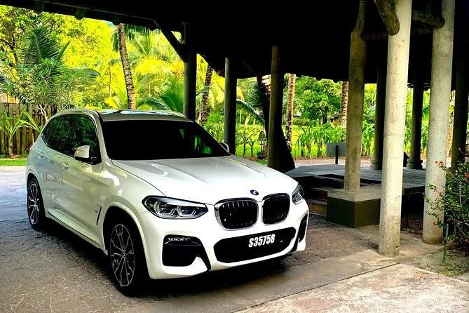 Ahşap bir pavyonun altında bekleyen açık renk premium araç, arkada orman