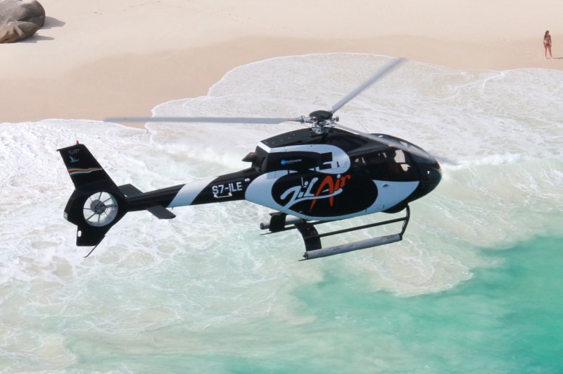 Turkuaz sığ bir koyun ve boş beyaz plajın üstünde alçaktan uçan Zil Air helikopteri