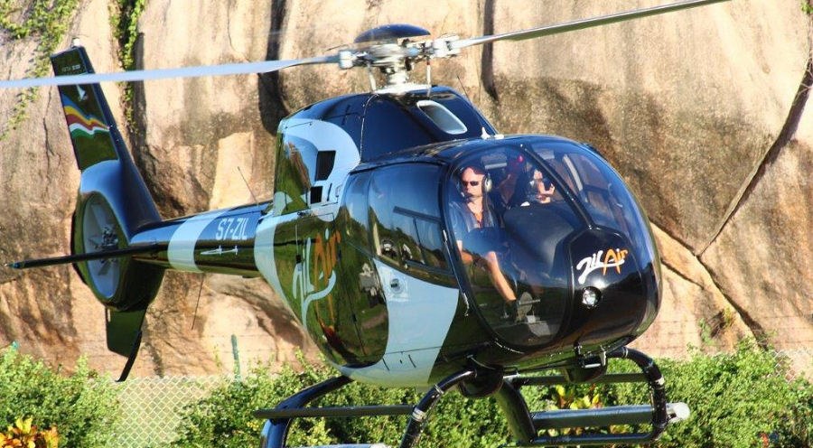 Granit kayanın yanında yerde duran Zil Air helikopteri, kabinde yolcular