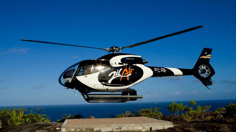 Kıyıdaki helipedin yanında havalanan Zil Air helikopteri, arkada açık deniz