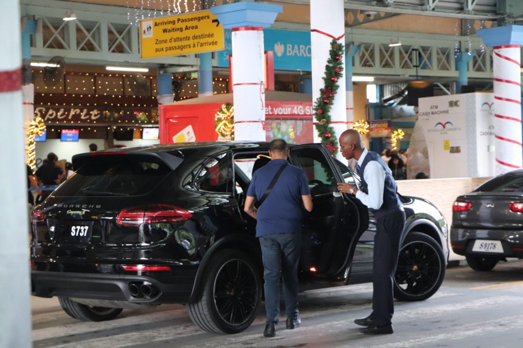 Seyşeller Uluslararası Havalimanı varış kapısında kapıyı tutan şoförle koyu renk premium araç